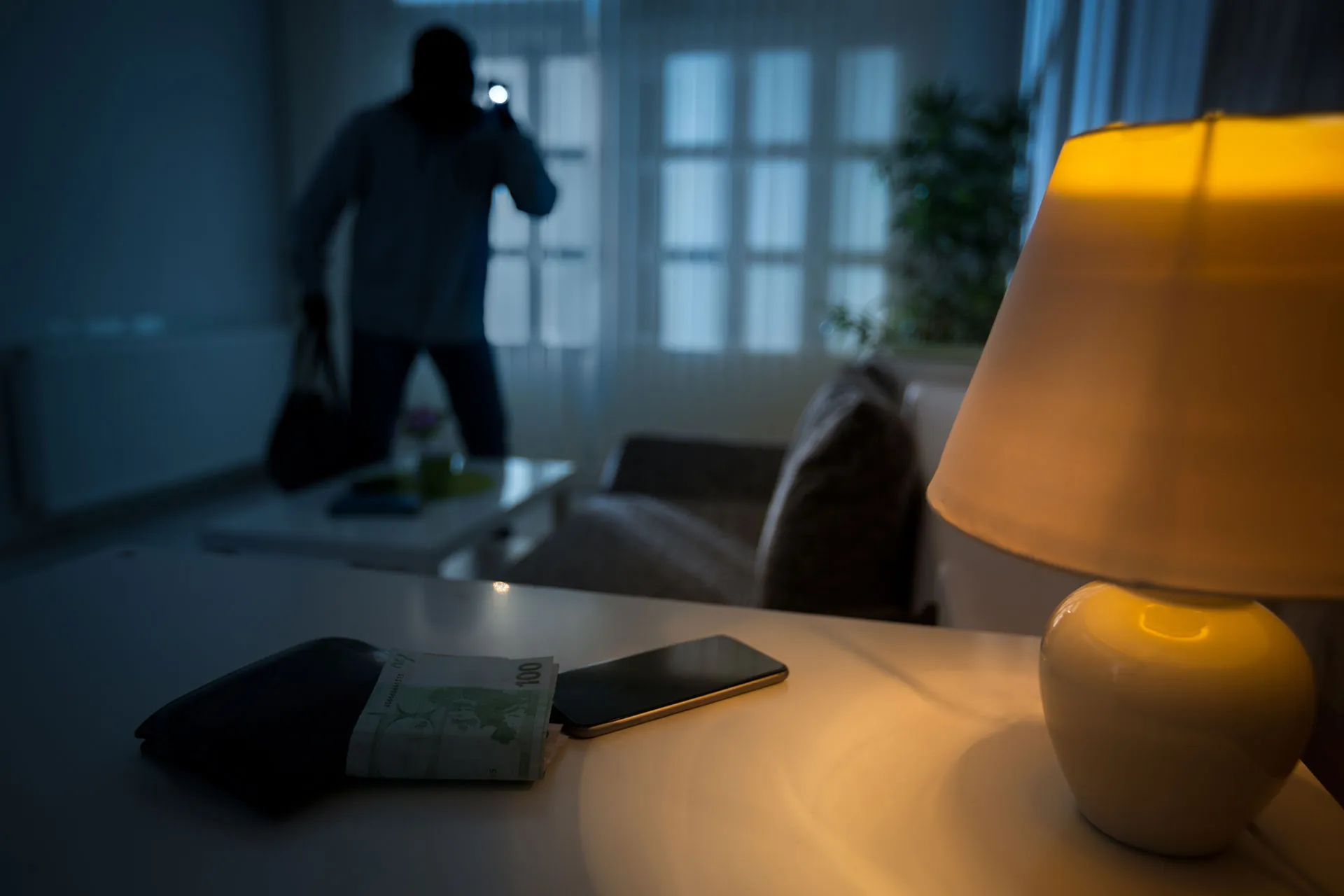 Silhouette einer Person am Fenster eines dunklen Wohnraums