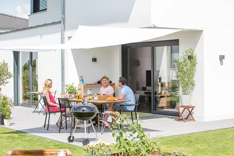 Terrasse mit verglastem Anbau und Sitzgruppe im Garten
